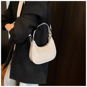 Close-up of cream woven crescent shoulder bag styled with a professional black blazer