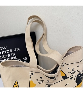 Detail of canvas tote bag featuring secure zipper closure and cute cartoon cat illustration