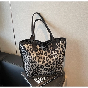 Detail of grey leopard print tote bag with black canvas straps on a chair