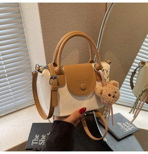 Close-up of contrast beige and brown bucket bag with bear charm and pebble grain texture