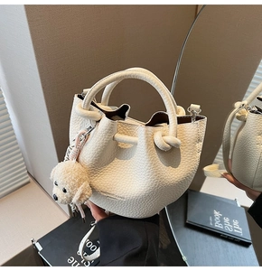 Detail of off-white lychee grain bucket bag with drawstring and teddy bear charm