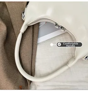 Detail of comfortable wide handle and smooth beige leather on crescent handbag