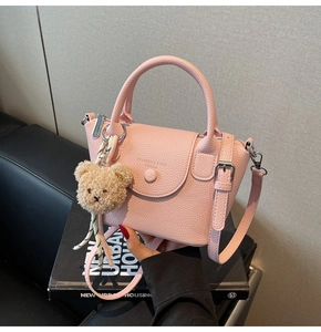 Detailed shot of pink pebble leather mini bucket bag with a cute bear charm accessory
