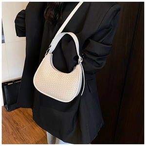 Detail of white woven hobo bag with adjustable strap on model in black suit
