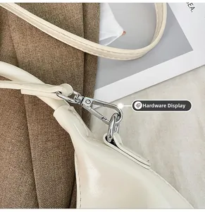 Detailed close-up of the polished silver hardware and strap hook on the white leather bag