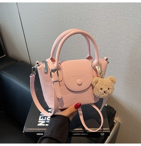 Gros plan détaillé du sac à main rose en cuir grainé avec breloque ours en peluche
