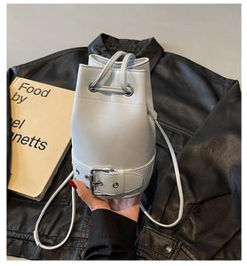 Détail du sac seau en cuir gris clair avec cordon de serrage et boucle décorative