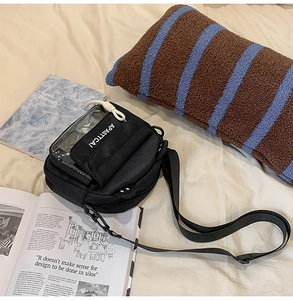 Détail du sac bandoulière en toile noire avec fenêtre PVC et sangle ajustable