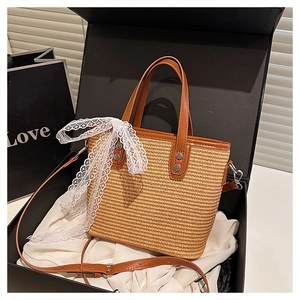 Detail of woven straw bag featuring brown PU leather handles and a white lace bow detail