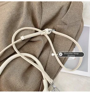 Detail of creamy white leather shoulder strap and polished silver metal clasp on the bag