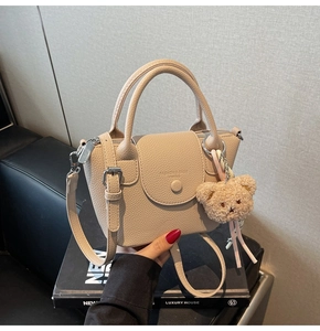 Détail du sac beige en cuir grainé avec un charm ours en peluche et des ferrures