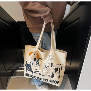 Close-up of a large beige canvas tote bag featuring cute cartoon cat and dog illustrations