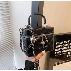 Detailed view of black quilted leather bag with heart charm and silver chain strap