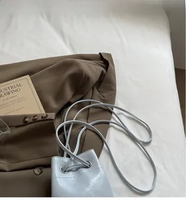 Détail du sac seau bleu clair en cuir huilé avec œillets métalliques et bandoulière