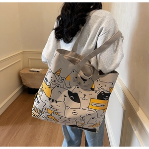 Side view of a large canvas tote bag with cute cat prints worn on a woman's shoulder