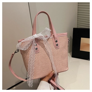 Detail of pink woven handbag featuring PU leather handle, metal rivets and a lace bow
