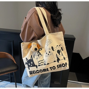 Detail of canvas tote bag with cartoon cat and dog illustration and plush puppy pendant
