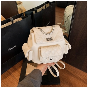 Detail view of cream quilted backpack featuring metal turn-lock and chain handle
