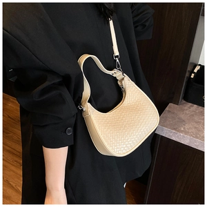 Close-up of beige woven crescent bag texture with silver zipper and leather shoulder strap