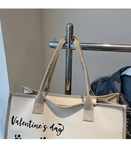 Detail der beigen Canvas-Einkaufstasche mit Valentinstag-Aufdruck und Gurtbandgriffen