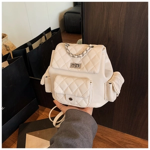 Detailed shot of beige quilted faux leather backpack with silver chain and turn-locks