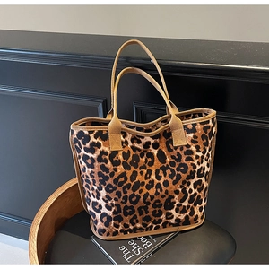 Detail of leopard print tote bag with brown fabric handles on a vintage chair