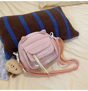 Détail d'un sac à bandoulière rose avec oreilles de chat et une poche en PVC transparent