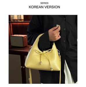 Detail of yellow leather baguette bag with bow and silver metal beads detail