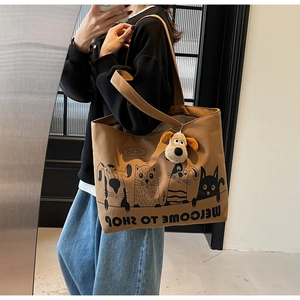 Detail of a brown canvas tote bag with cartoon pets and a 3D plush dog charm accessory