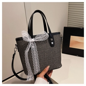 Close-up of woven texture and white lace bow detail on a stylish black tote bag