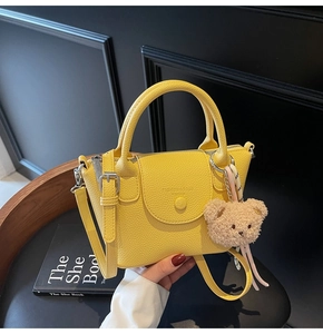 Detail of yellow lychee pattern handbag with top handle and plush bear charm
