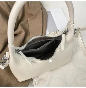 Close-up of beige handbag interior showing zipper pocket and silver metal hardware