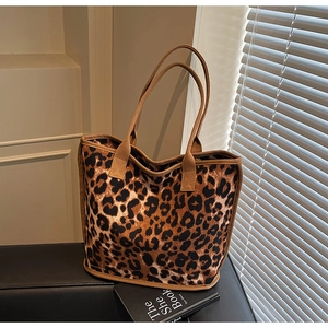Close-up of leopard print tote bag featuring fuzzy texture and brown canvas handles