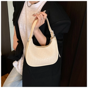 Close-up of beige woven crescent bag showing intricate texture and premium leather strap