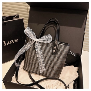 Detail of woven bucket bag with lace bow accessory in a premium black gift box set