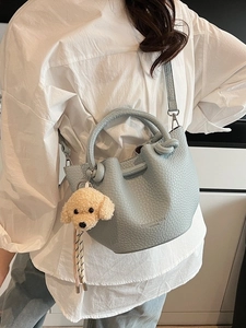 Light blue lychee textured leather bucket bag with dog pendant and detachable strap