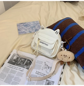 Détail du sac bandoulière blanc à oreilles de chat avec lettrage et porte-clés peluche
