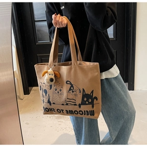 Detail of khaki canvas tote bag with cartoon print and plush dog keychain pendant