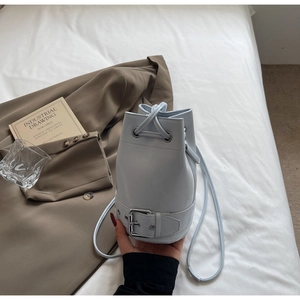 Détail du sac seau bleu clair avec fermeture à cordon et boucle décorative au bas
