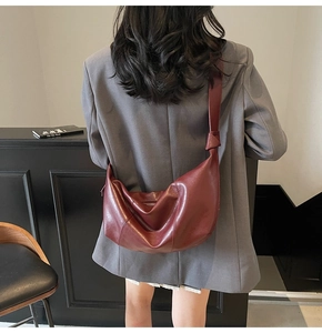 Detail of dark red half-moon shoulder bag with unique knot design and matte leather finish
