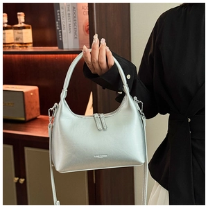 Close-up of a silver crescent-shaped leather handbag with double zipper and sleek handle