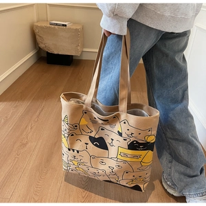 Detail of canvas tote bag showing cat pattern, durable top handle, and zip closure