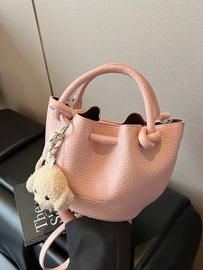 Pink lychee textured bucket bag with knot handle and plush puppy charm for women