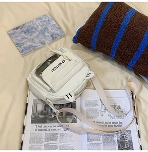 Détail d'un sac à bandoulière blanc avec oreilles de chat et poche frontale transparente