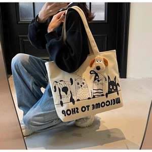 Detailed shot of beige canvas tote bag featuring cartoon animal prints and plush dog charm