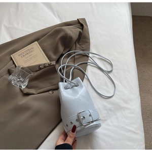 Détail du sac seau bleu clair avec fermeture à cordon et ceinture à boucle argentée
