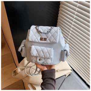 Detail of light blue quilted leather backpack with silver metal turn-lock and chain handle