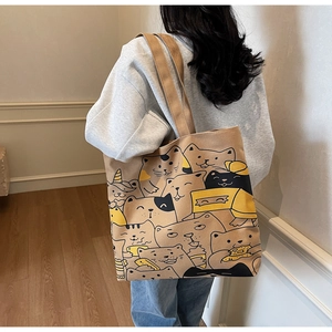 Detail of khaki canvas tote bag featuring cute cartoon cat prints on mannequin's shoulder