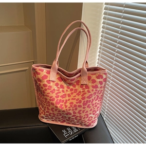 Detailed view of pink leopard print canvas tote bag on leather sofa with soft lighting