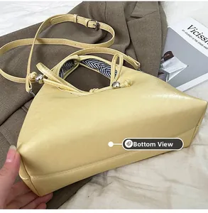 Detailed bottom view of the light yellow triangular handbag with black and white lining